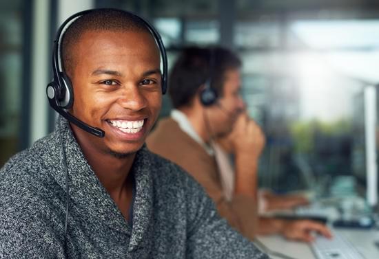 Male Call centre agent smiling talking to a customer through his headset