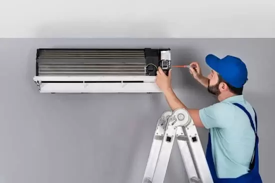 Indoor wall mounted residential air conditioning unit being serviced by a technician